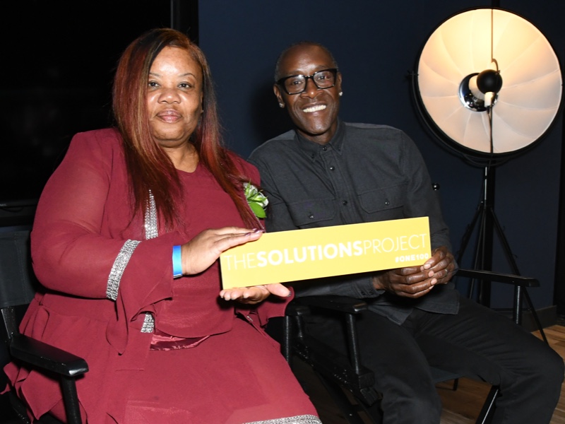Don Cheadle and a woman holding a sign together that says 