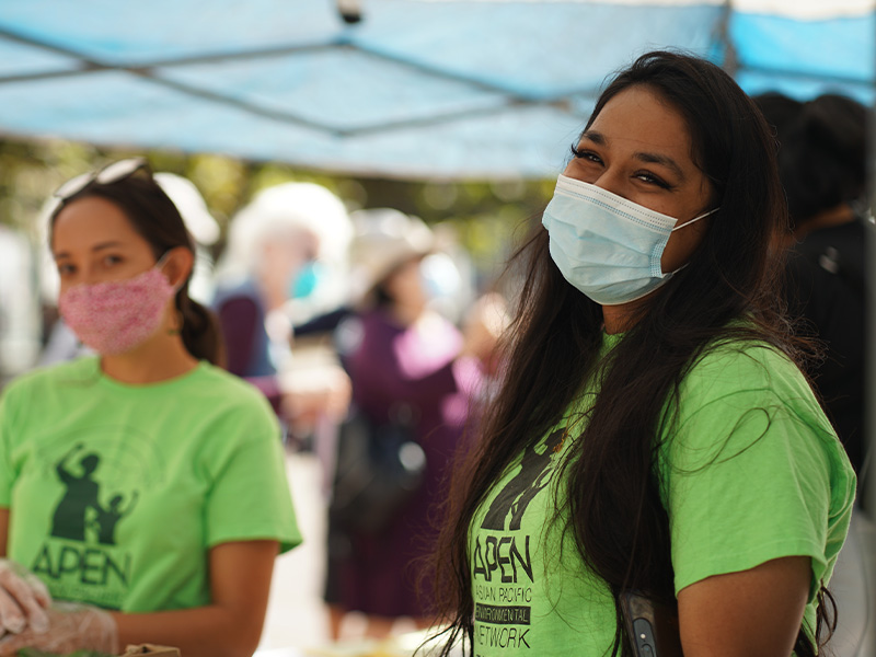Two women in masks, one is smiling.