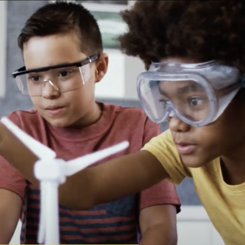kids gathered around model wind turbines